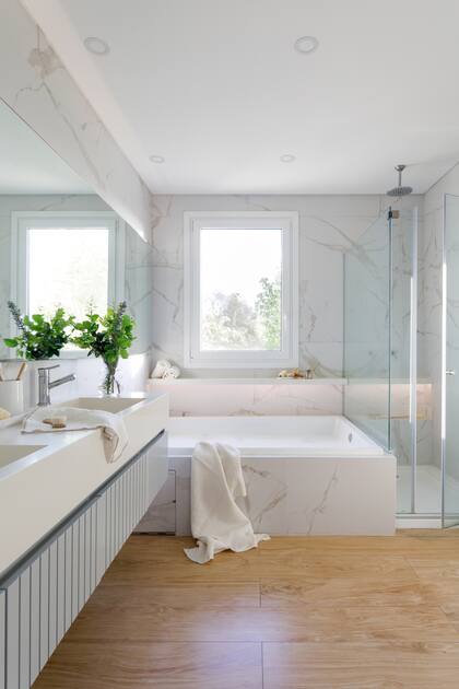 En el baño, revestimiento (Vite). Mesada de Purastone (Cavatori). Mampara (Glassic). Hidromasaje (Ferrum). Bata y toallas (Lote Propio).Las mesadas blancas y los muebles en gris claro complementan el dibujo del porcelanato y su veta suave.