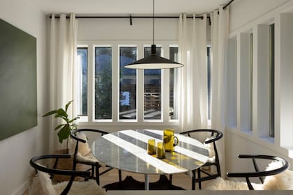 En el comedor diario con mesa Tulip reaparece el verde, en una obra que los dueños de casa pintaron juntos.