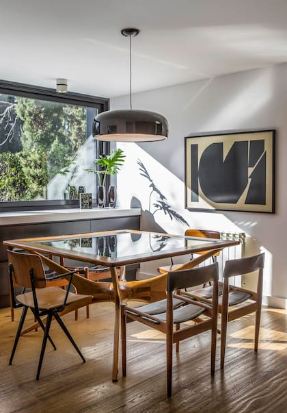 En el comedor diario, mesa con tapa de vidrio (Santiago del Campo), sillas (Un Lugar Así), luminaria colgante de aluminio con difusor ‘Smithfield’ (Iluminación Agüero) y lámina enmarcada