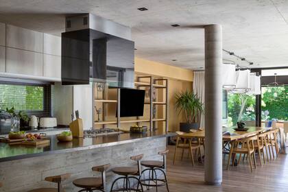 En el comedor, mesa de 4 metros, sillas de teca y mueble de TV de hierro y pino canadiense (todo de Hugo Tonti). Lámparas ideadas por los dueños, con estructura de hierro realizada por Tonti. Para la pared de ese sector eligieron un entelado de arpillera (Oscar Favre).