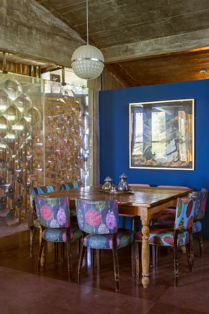 En el comedor, mesa hecha a medida con madera reciclada y sillas de estilo retapizadas con telas que compraron en Ikea Brasil. Pañuelo de seda del Museo Frida Kahlo (México), con marco dorado a la hoja. La lámpara de cristal checo es original.