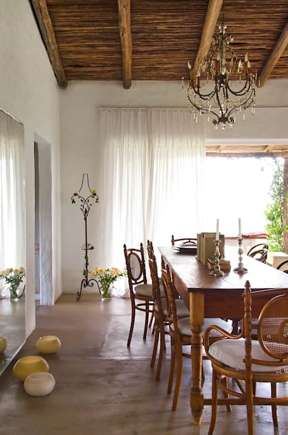 En el comedor, mesa rústica con distintos modelos de sillas Thonet compradas en una feria de antigüedades de Montevideo. Como centro, una graciosa biblioteca armada con los libros que invariablemente olvidan sus invitados.