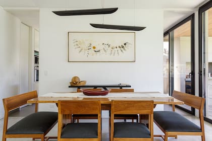 En el comedor se destaca el tono de madera que aportan la mesa (Estudio V) y las sillas tapizadas (Bull Buenos Aires). Obra de Cuqui Wegner para Mundo Apología