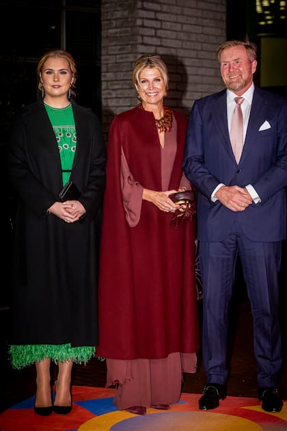 En el concierto, la reina de los Países Bajos, siempre impecable, optó por un mono manga larga de Natan, que acompañó con una capa a tono de Valentino, guantes de cuero, collar dorado, clutch de Zara y stilettos Gianvito Rossi. Aqui la vemos junto a su hija y su marido, el rey Guillermo Alejandro