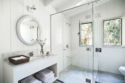 En el cuarto de baño, el brillo de materiales como el mármol, el vidrio y la cerámica compensan la cualidad rústica de la madera.