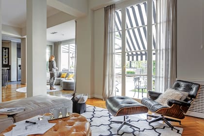 En el cuarto de la tele, un sillón Miller y un revistero (Magnolia). Puf de cuero capitoné (Créole).