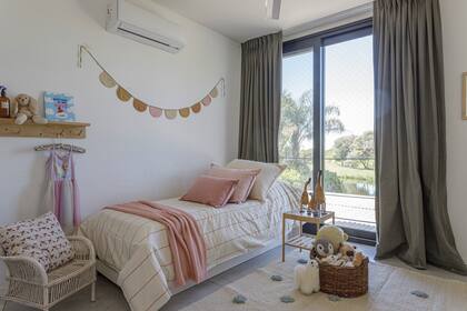 En el cuarto de las chicas, cortinas gris caldén (Tienda Mayor) y ropa de cama en blanco y rosa (Teodolina Deco). Sillón de mimbre pintado. Para la hora de jugar, alfombra tejida con pompones (Elementos Argentinos)