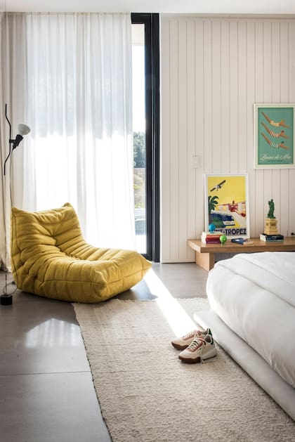 En el cuarto de una de las hijas, el modelo ‘Parentesi’ de pie (Flos) y sillón ‘Togo’ color mostaza.