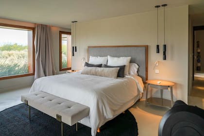 En el cuarto se combinan las mesas de luz laqueadas (Quintana Casa) y anqueta de aluminio (Harturo) con piezas hecha sa mano como las lámparas de madera torneada (Fabrica de luz) y alfombras tejidas a mano (Elementos Argentinos).