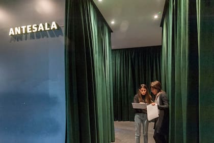 En el día de los ensayos generales, intercambio previo en el pasillo que conduce a las salas