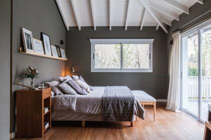 En el dormitorio con salida a una terraza propia y con escritorio integrado, mesas de noche (Laura O) y cuadros (Organizza).