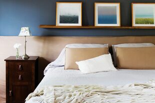 En el dormitorio principal, corren en paralelo las líneas del tríptico de fotografías, el estante de madera que las sostiene y el cabezal de la cama, bajo y extendido hacia los costados.