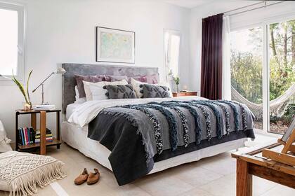 Almohadones (Rosario Solano), almohadas (Everything), manta gris (Zara Home) y handira gris (Kasbah). Mesa de luz (Breuer Moreno). Alfombra (Rugit). Almohadón gigante tejido en macramé con flecos (Vero Alessandrini).