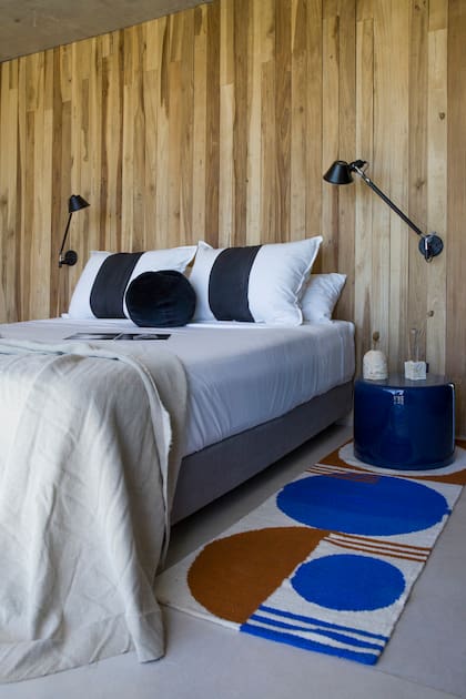 En el dormitorio principal, almohadones y género (Mercedes Segura), alfombra (Caucus Lab), mesas de luz de chapa pintada al horno en azul brillante (Victoria D’Ornellas). Floreros (Pilar Urruti Studio).