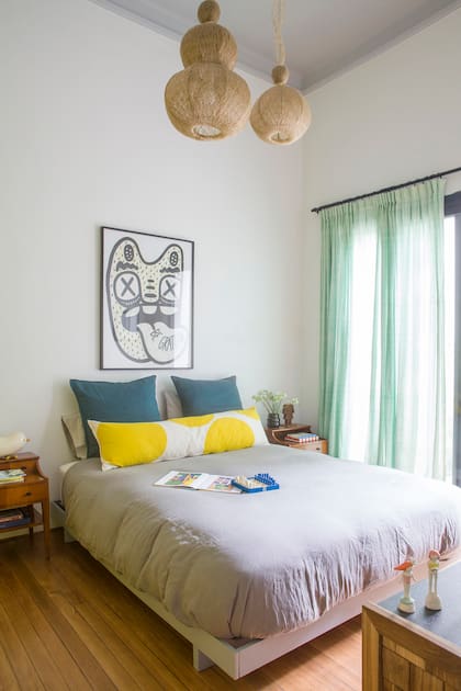En el dormitorio y el baño principal se apostó por el gris y el amarillo, una dupla que le encanta a la dueña de casa. Lámparas ‘Farola’ (La Feliz), una obra de Pola (Somos Yunta) y mesas de luz compradas en un remate.