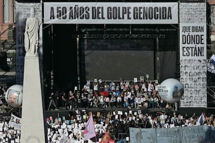 En el escenario miembros de la asociación de derechos humanos Madres de Plaza de Mayo sostienen los retratos de sus hijos e hijas desaparecidos