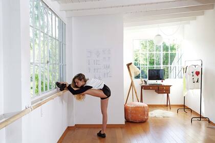 La sala donde Luna practica y da clases de danza tiene piso de madera con cámara de aire. Además, hay una zona de estudio equipada con un escritorio vintage para la compu, lámpara de pie ‘Citripio’ (Talleres Sustentables) y puf con pátina en color cobre (MS Deco).