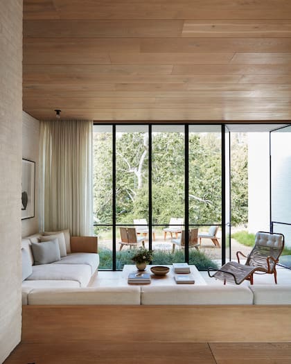 En el family room se replica la estética del living (aunque sin alfombras ni pisos de madera), con sillones y mesa de arrime y una chaise longue encordada. El espacio se integra con un living exterior con fogonero que invita a disfrutar del afuera.