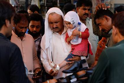 Un hombre prueba una sandalia a su hija en medio de las celebraciones de Eid al-Fitr durante el brote de la enfermedad por coronavirus, en Karachi
