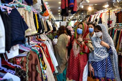 Mujeres con barbijos en una tienda de ropa de Karachi, en Paquistán