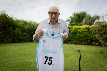 En el jardín de la casa de su hija, en la que vive, posa con la camiseta que le regaló la Confederación Argentina de Básquetbol por los 75 años de la conquista del Mundial Argentina 1950; es el único sobreviviente del plantel.