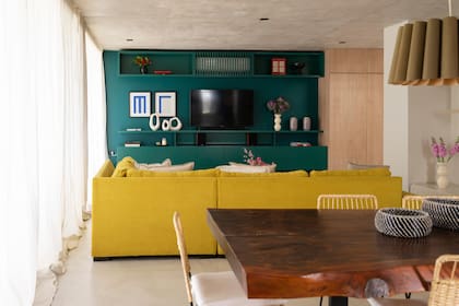 En el living, el sillón amarillo es protagonista. Almohadones, centro de mesa, jarrón y manta conjugan materiales nobles y tonos tierra (todos de @salazarcasa). Arreglo floral (@blomsterflower)