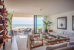 En el living –que tiene un ventanal con una espectacular vista al océano–, el minimalismo se mezcla con el lujo. Los sillones en color crudo, los muebles a medida, diseñados por Federico Álvarez Castillo, y las lámparas italianas enmarcan un espacio en el que el paisaje también es protagonista.