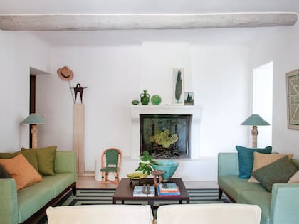 En el llamado “living de invierno”, la chimenea original se modernizó con un frente de obra redondeado y encalado. El motivo de la alfombra se asocia con el diseño del jardín laberíntico de uno de los cuadros.