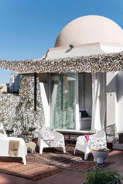 En el paso de la terraza al living, muebles de exterior en PVC (Casa The Stock). Toldo (Mechi Hunter).