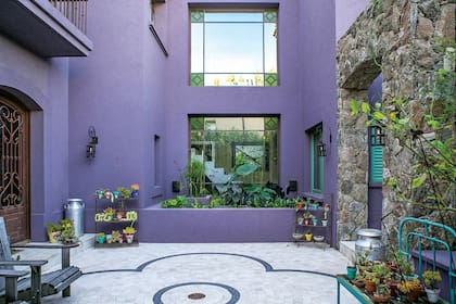 En el patio de acceso, piso de baldosas de Travertino con dibujo en mármol negro. Un estanque con papiros y lirios. Sillones de guayubira con tratamiento drift para exteriores (Profunda Decoración).