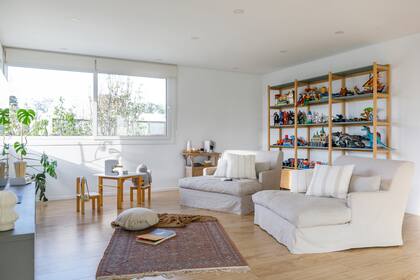 En el playroom, estantería (Ukelele). Alfombra persa antigua (Decovintage New). Almohadones y manta (Lote Propio). Juguetes artesanales en madera. (Lola y Chango).