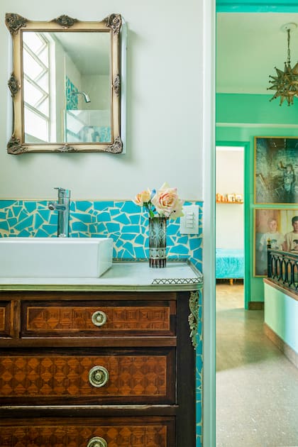 En el primer piso, el baño conserva sus azulejos originales color turquesa, pero rotos y vueltos a pegar. Una cómoda antigua sirvió de base para el vanitory.