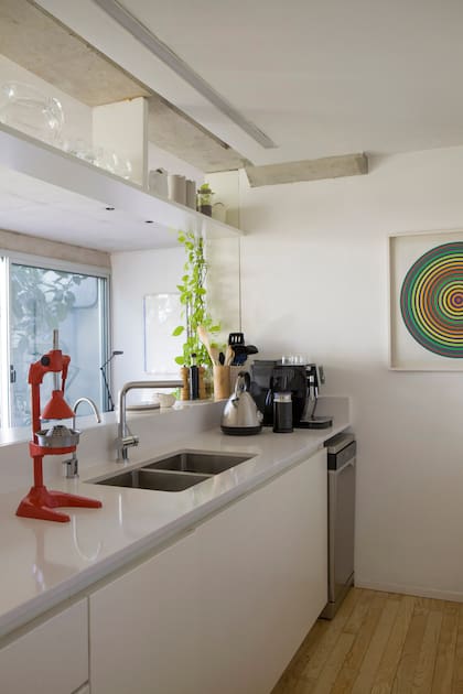 En el remate de la cocina, serigrafía de Julio Le Parc. Entre el blanco de las terminaciones se luce un antiguo exprimidor naranja, parte de las piezas de colección que los dueños de casa disfrutan poner en valor.