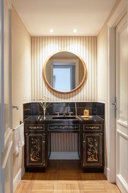 En el toilette, entelado con un género rayado, se incorporó un mueble pintado con inspiración china, mesada de mármol (De Stefano) y espejo circular