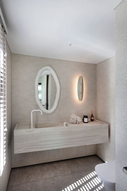 En el toilette se usaron los mismos materiales del hall y la cocina. Una mesada imponente y sin soportes laterales crea la ilusión de estar suspendida en el aire, y la grifería de monocomando remoto complementa este efecto.