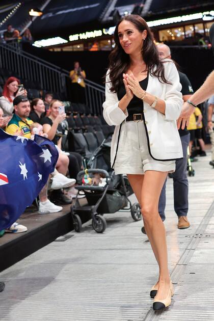 En ese encuentro, Meghan impactó con un conjunto de blazer de punto con borde a contratono y botones dorados de J-Crew, bermudas de lino Staud, sandalias slingbacks Chanel, cinturón Givenchy y aros de diamantes Anita Ko.