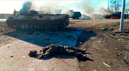En esta captura de un video publicado por el Servicio de Prensa del Departamento de Policía de Ucrania, el cuerpo de un soldado muerto yace en el suelo junto a vehículos militares destrozados después de un ataque presuntamente perpetrado por separatistas o rusos en el este de Ucrania, el jueves 24 de febrero de 2022
