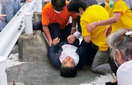 En esta captura de video, el ex primer ministro japonés Shinzo Abe, en el centro, es atendido en el suelo luego de recibir un disparo en Nara, al oeste de Japón el viernes 8 de julio de 2022.