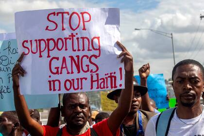 En esta foto de archivo del 10 de diciembre de 2020, un manifestante alza un cartel con la leyenda, en inglés, "dejen de apoyar a las pandillas en nuestro Haití". 