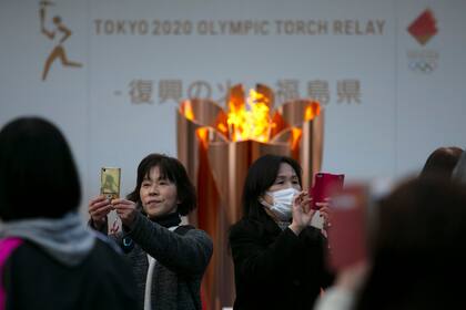 En esta foto de archivo del 24 de marzo de 2020, la gente toma fotos con la Llama Olímpica durante una ceremonia en la ciudad de Fukushima, Japón.