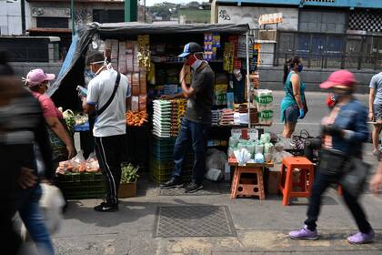 En esta foto de archivo tomada el 2 de abril de 2020, las personas usan mascarillas en un mercado como medida preventiva contra la propagación del nuevo coronavirus, en el barrio de Petare en Caracas