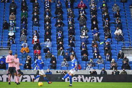 En esta foto de archivo tomada el 20 de diciembre de 2020, los fanáticos, con máscaras debido a la pandemia de coronavirus, se sientan socialmente distanciados durante el partido de fútbol de la Premier League inglesa