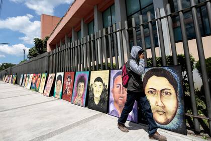 En esta foto de archivo tomada el 24 de septiembre de 2015, un estudiante pasa por delante de los retratos de algunos de los 43 estudiantes desaparecidos de la escuela normal rural de Ayotzinapa colocados por sus compañeros frente al Congreso del estado de Guerrero en Chilpancingo, México, tras una marcha desde la escuela.