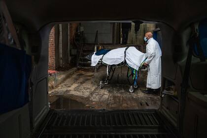 En esta foto de archivo tomada el 24 de diciembre de 2020, el transportista de Maryland Cremation Services, Reggie Elliott, lleva los restos de una víctima del Covid-19 a su camioneta desde la morgue del hospital en Baltimore, Maryland