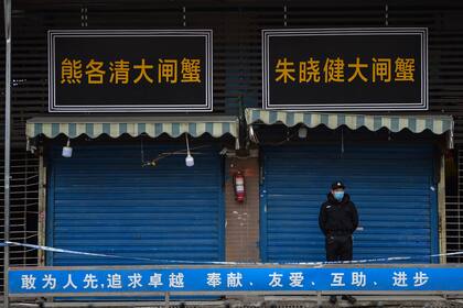 En esta foto de archivo tomada el 24 de enero de 2020, un guardia de seguridad se encuentra frente al mercado mayorista de mariscos de Huanan, donde se detectó el coronavirus por primera vez en Wuhan