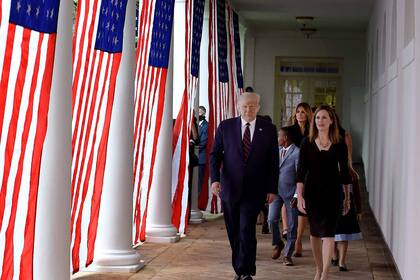 En esta foto de archivo tomada el 26 de septiembre de 2020, Donald Trump (izquierda) y la jueza Amy Coney Barrett (derecha), con la primera dama de Estados Unidos, Melania Trump, llegan al jardín de rosas de la Casa Blanca en WashingtoN