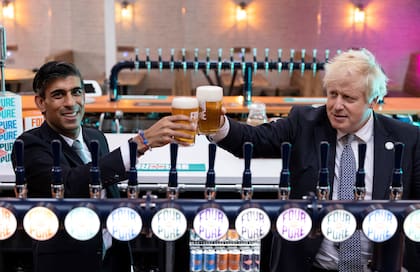 En esta foto de archivo tomada el 27 de octubre de 2021, el primer ministro británico Boris Johnson y el canciller británico Rishi Sunak brindan con una pinta mientras visitan la cervecería Fourpure en Bermondsey, en el sur de Londres.