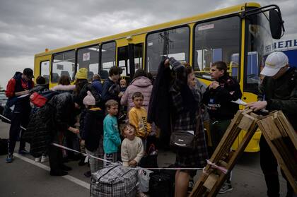 En esta foto de archivo tomada el 29 de abril de 2022, familias procedentes de los territorios ocupados por Rusia en la región de Zaporizhzhia llegan en un convoy humanitario a un centro de registro y procesamiento de desplazados internos en medio de la invasión militar rusa lanzada sobre Ucrania.