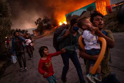 En esta foto de archivo tomada el 9 de septiembre de 2020 una familia de migrantes abandona el campamento de Moria después de que estallara un incendio en la isla de Lesbos