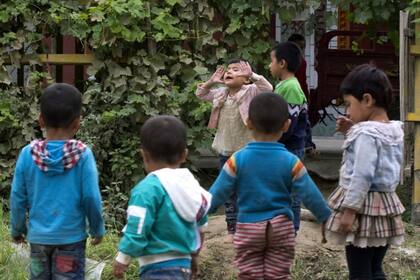 En esta foto del 30 de agosto de 2018, los niños uigures juegan al aire libre en Hotan, en la región occidental de Xinjiang de China